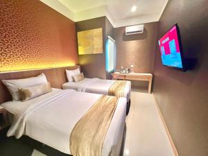 a hotel room with two beds and a flat screen tv at Deli Hotel in Medan