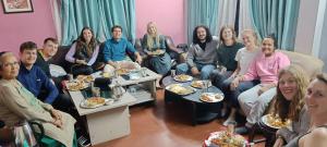 a group of people sitting in a living room eating food at KIRTIPUR COMFORT HOMESTAY with breakfast & dinner in Kirtipur