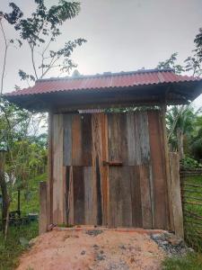 un cobertizo de madera con techo rojo sobre una pila de tierra en Banteay Srey Women's Only Traditional Spa and Homestay en Kampot