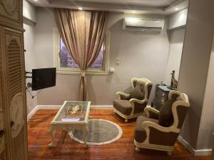 ein Wohnzimmer mit 2 Stühlen, einem Tisch und einem TV in der Unterkunft المهندسين شقه سوبر لوكس - محى الدين ابو العز in Kairo