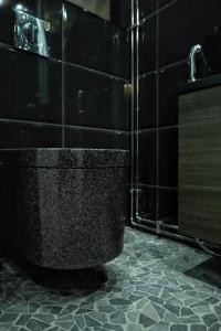 Łazienka z czarną toaletą i czarną podłogą wyłożoną kafelkami w obiekcie Villa Auroras Poro w mieście Syöte