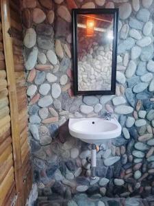 a stone bathroom with a sink and a mirror at Mecaja Beach House in Roxas