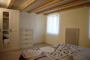 a bedroom with a bed and a dresser and a window at Alla Valle in Gallio