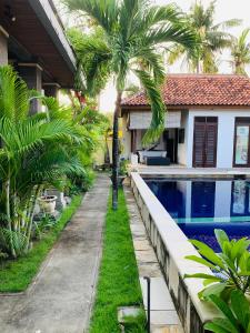 a house with a swimming pool and palm trees at Pondok Baruna Garden in Nusa Lembongan