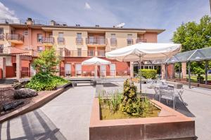 cortile con tavoli e ombrelloni di fronte a un edificio di HOTEL LA PERLA a Olot