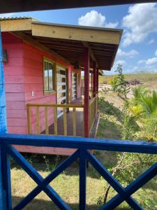 Casa pequeña de color rosa con porche de madera en Villasollagoinha, en Paraipaba