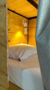 a bed in a room with a wooden wall at Hostel Hug Brasil in Curitiba