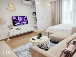 a white living room with a bed and a tv at YLY Homestay Hạ Long in Ha Long