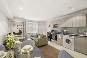 eine Küche und ein Wohnzimmer mit einem Tisch und Stühlen in der Unterkunft LiveStay - Apartments in Bayswater London in London