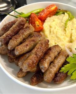 a plate of food with sausage and mashed potatoes and vegetables at Transilvania Garden House in Miercurea-Ciuc
