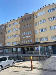 Un gran edificio con un coche aparcado delante. en Holidays, Arttyfal, 2 Dormitorios para 4 personas, parking y wi-fi, en Sierra Nevada