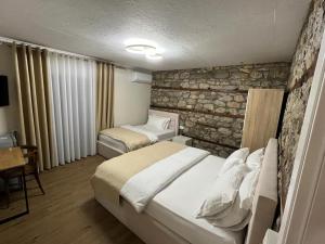 a bedroom with two beds and a stone wall at Vila Ndrio in Pogradec