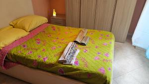 a bed with a green comforter and a book on it at Licheni house in Rome