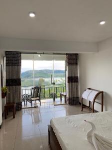 a bedroom with a bed and a balcony with a view at The Station Lodge in Haputale
