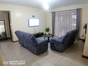 sala de estar con 2 sillas azules y mesa en AMOR LAKEBREEZE 3, en Kisumu