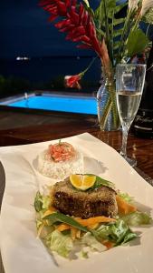 einen Teller mit Essen auf einem Tisch mit einem Glas Wein in der Unterkunft El Caribeo in Bocas del Toro