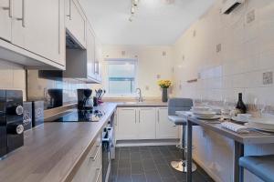 eine große Küche mit weißen Schränken und einer Arbeitsplatte in der Unterkunft Elegance Graceland in Gillingham