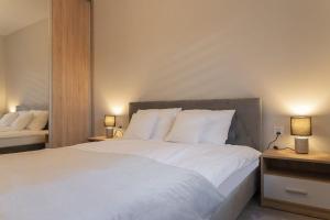 een slaapkamer met een groot wit bed met 2 lampen bij VacationClub – Spokojna 24I Apartament 1 in Wisła
