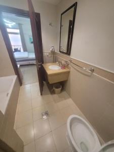 een badkamer met een wastafel, een toilet en een spiegel bij Royal Beach Apartment in King Abdullah Economic City