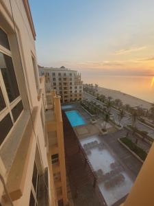Royal Beach Apartment في King Abdullah Economic City: اطلالة جوية على مبنى به مسبح و المحيط