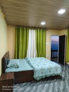 a bedroom with a large bed with green curtains at RKD HOMESTAY in Kurseong