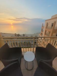 Royal Beach Apartment في King Abdullah Economic City: شرفة مع كراسي وطاولة على شرفة