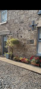 un edificio de piedra con flores y una cruz. en 1850s Character Stone Cottage, en Mold