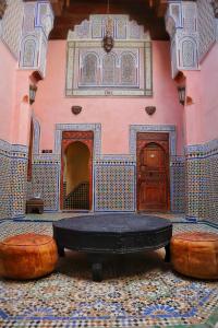 a room with a large bed and two ottomans at Riad D'or meknes in Meknès