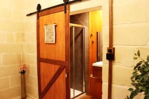 porta in legno in bagno con specchio di Il-Bàrraġ Farmhouse B&B - Gozo Traditional Hospitality a Nadur