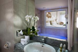 
a bathroom with a sink, mirror, and tub at Azia Resort & Spa in Paphos
