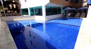 een groot blauw zwembad in een gebouw bij Praia dos Carneiros flat hotel in Tamandaré