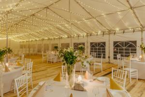 una marquesa con mesas blancas, sillas y luces en Country Club Żywiec Hotel i Domki Całoroczne, en Żywiec