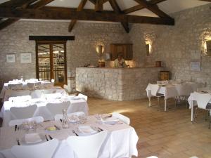 un comedor con mesas blancas y un hombre en la cocina en Château Lecusse - La Grande Roche - Hôtel, Spa, Boutique & Restaurant, en Broze