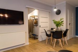 uma sala de jantar com mesa e cadeiras e uma televisão em VacationClub – Spokojna 24E Apartament C.1 em Wisla