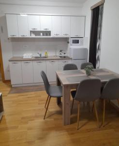 een keuken met witte kasten en een tafel en stoelen bij KONAK ViLA MIRKOVIĆ in Soko Banja