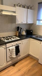 cocina con armarios blancos y fogones en Cosy Apartment in London en Londres