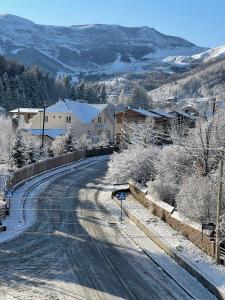 una carretera cubierta de nieve con una casa y una montaña en Hotel King David Bakuriani en Bakuriani