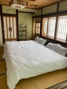 a large white bed in a room with windows at やすらぎの宿 菜の香 in Biei