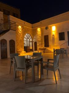 einen Tisch und Stühle auf einer Terrasse in der Nacht in der Unterkunft ARTUKHAN BUTİK HOTEL in Mardin