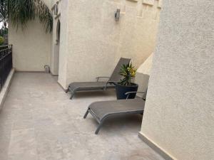 3 sillas sentadas en un porche con una planta en Villa Bohème avec personnel de maison, en Marrakech