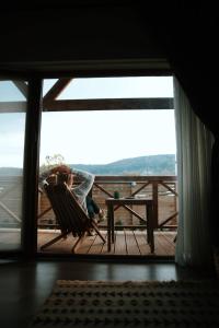 eine Person, die in einem Schaukelstuhl auf einer Terrasse mit einem Tisch sitzt in der Unterkunft Abant Cozy Homes in Bolu