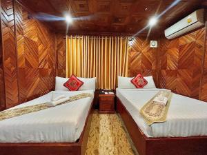 two beds in a room with wooden walls at HONG PEP HOTEL in Battambang
