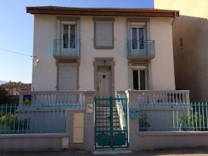 una casa blanca con una valla azul y una puerta en Villa atmosphère à l'ile verte en Grenoble