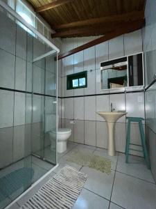 a bathroom with a glass shower and a sink at Embausurf - Moradas de Aluguel in Guarda do Embaú
