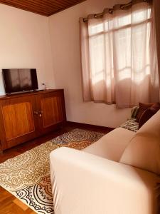 uma sala de estar com um sofá e uma televisão em Cantinho do sossego em Campos do Jordão