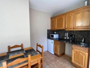 a kitchen with wooden cabinets and a table and a sink at Wuau! Apartamentos Solana de Ransol in Ransol