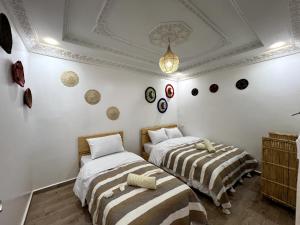 2 camas en una habitación con paredes blancas y techo en traditional taghazout surf en Taghazout