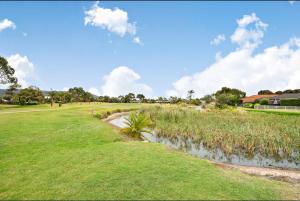 a grassy field with a creek in the middle at Golf Spa Retreat in Safety Beach