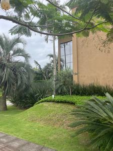 a building with palm trees in front of a yard at Suite em linda casa em Jurerê internacional in Florianópolis