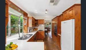 een keuken met houten kasten en een witte koelkast bij Spacious, Modern & Stylish Vacation Home in Seaton